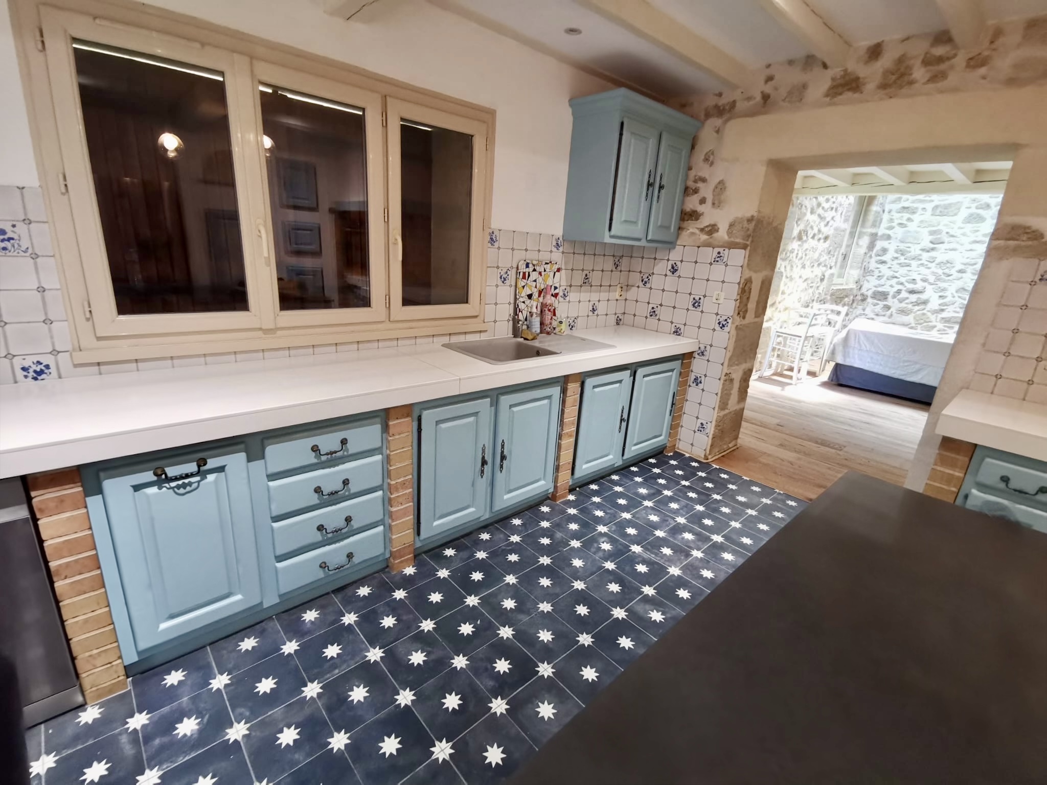 Cuisine rénovée avec meubles bleus et sol en carreaux de ciment à Bordeaux