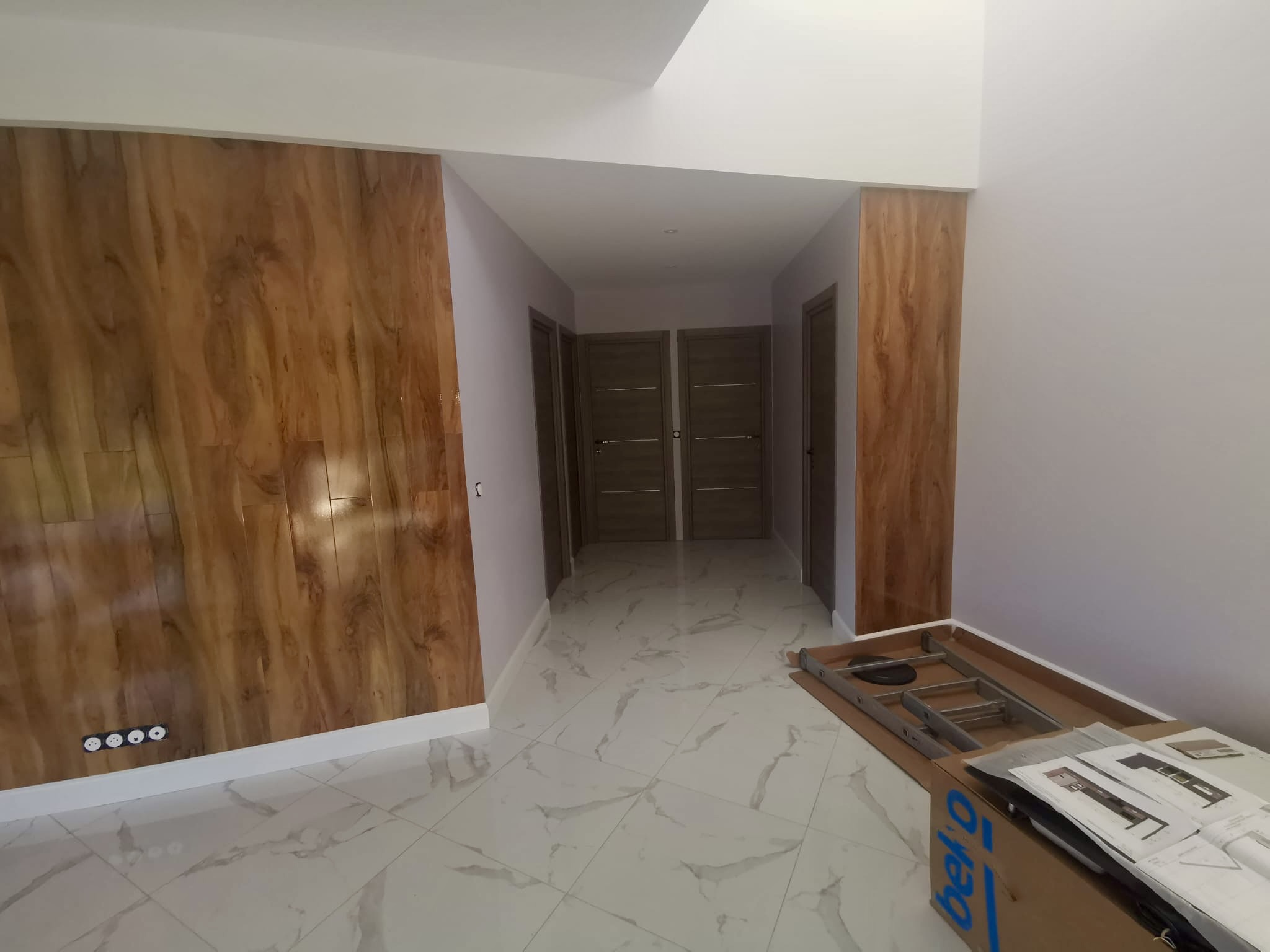 Couloir rénové avec mur en bois et sol effet marbre à Bordeaux
